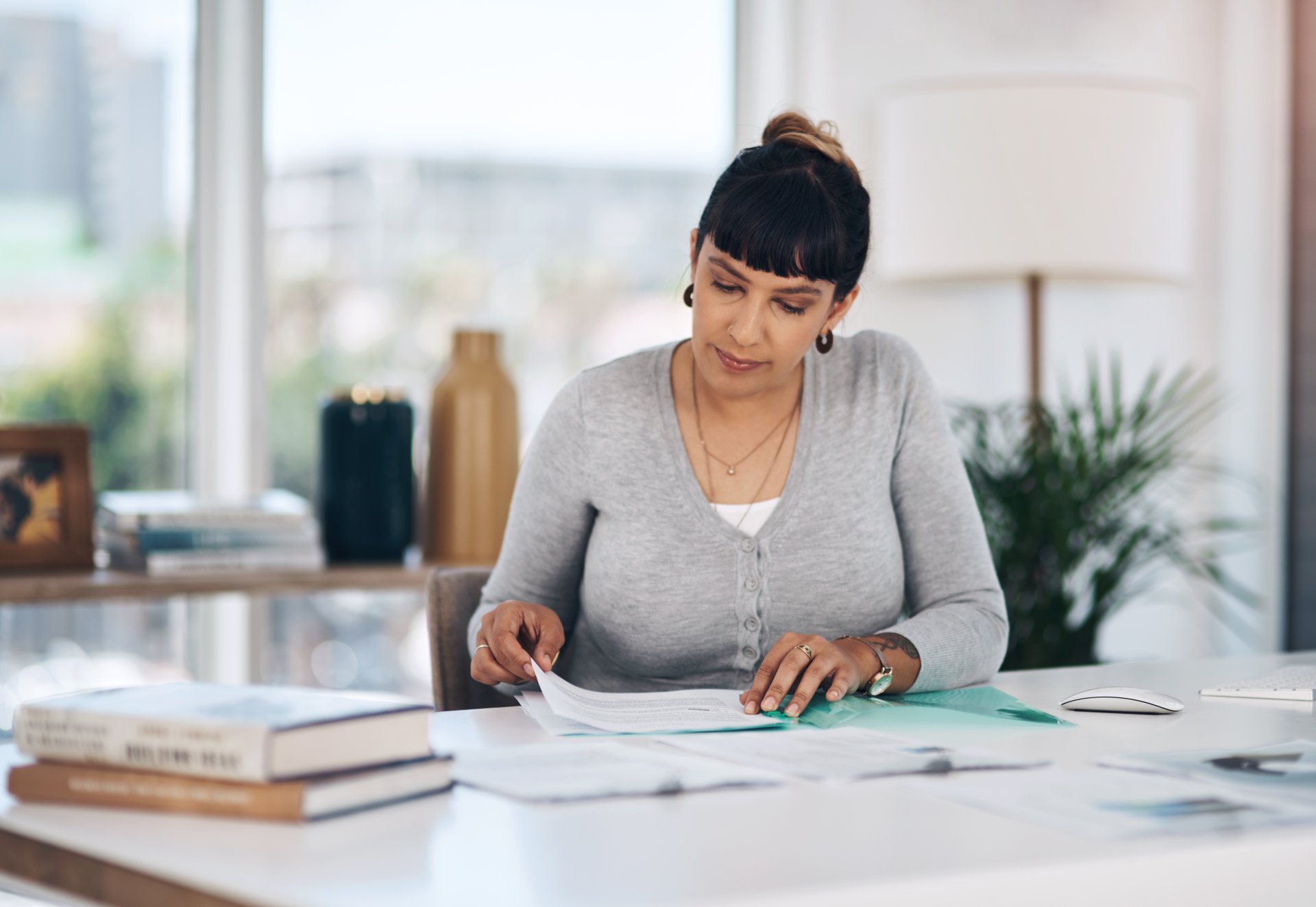 Empresária analisando documentos do contrato social da empresa sobre a mesa do escritório